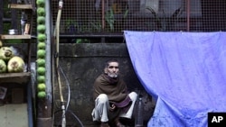 A man sits outside his makeshift shelter at the side of a road in Mumbai, India, Sept. 21, 2011.