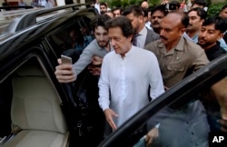 FILE - A Pakistani takes selfie with Imran Khan, center, head of the Pakistan Tehreek-e-Insaf party, as he leaves a party meeting in Islamabad, Pakistan, Aug. 6, 2018.