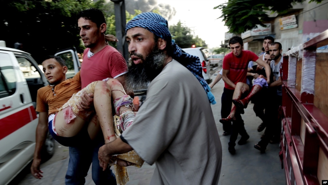 Warga Palestina menggendong seorang anak yang terluka dalam serangan Israel di Gaza, menuju ambulans hari Rabu (30/7).