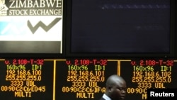  A Zimbabwe Stock Exchange official walks past an electronic display screen showing an 11-percent drop at the close of trading, Harare, Aug. 5, 2013.