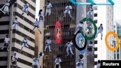 Acrobats on Olympics rings and lifted musicians perform as the Olympic torch is relayed along Paulista Avenue in Sao Paulo's financial center, Brazil, July 24, 2016. 