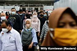 Para calon penumpang mengenakan masker, berjalan menuju platforn kereta komuter pada jam sibuk sore hari, di tengah merebaknya varian omicron di Jakarta, 3 Januari 2022. (REUTERS/Willy Kurniawan)