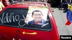 Pendukung Presiden Hugo Chavez di Caracas memasang foto Chavez di mobilnya dengan tulisan: 'Dia Telah Kembali', Senin (18/2). 