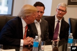 Apple CEO Tim Cook, right, and PayPal founder Peter Thiel, center, listen as President-elect Donald Trump speaks during a meeting with technology industry leaders at Trump Tower in New York, Dec. 14, 2016.