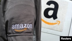 FILE - An Amazon.com Inc driver stands next to an Amazon delivery truck in Los Angeles, California, U.S.
