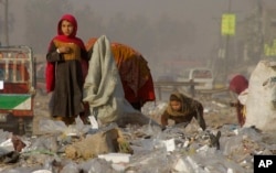 FILE - Afghan refugees girls collect recycle-able goods from a garbage to sell and earn living for their families in Peshawar, Pakistan, Feb. 5, 2016.