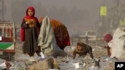 FILE - Afghan refugees girls collect recycle-able goods from a garbage to sell and earn living for their families in Peshawar, Pakistan, Feb. 5, 2016.