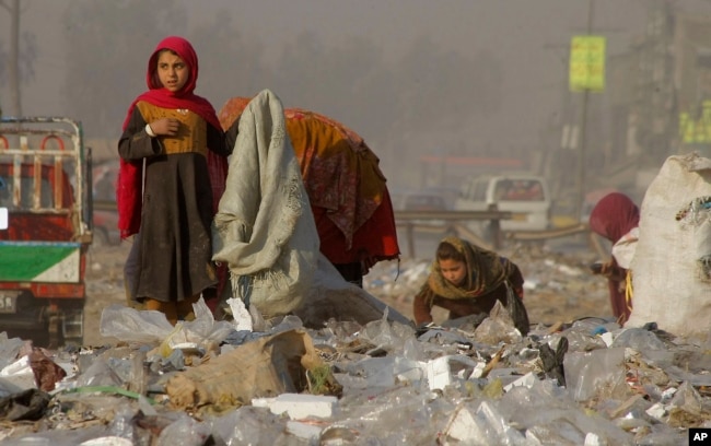 FILE - Afghan refugee girls collect recyclable items from garbage to sell to help sustain their families in Peshawar, Pakistan, Feb. 5, 2016. The conflicts in Syria, Afghanistan, Somalia and elsewhere are churning out millions of desperate and vulnerable people susceptible to traffickers.