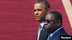U.S. President Barack Obama and Senegalese President Macky Sall (R) watch a military band play at the airport in Dakar, Senegal, June 28, 2013.