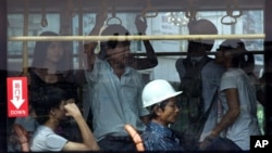 A commuter wears a construction helmet while sitting inside a crowded bus in Zhanjiang, China's Guangdong province, June 28, 2012.