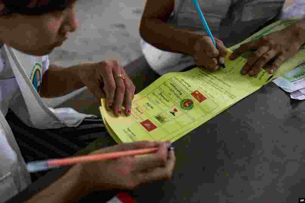 Volunteers prepare ballots for voters at a polling station in Dala, a village outside of Yangon, Nov. 8, 2015.