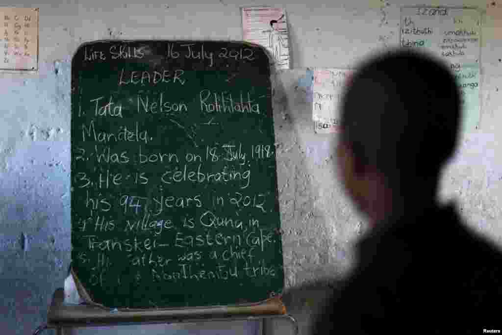 C&aacute;c em học sinh đọc lịch sử về &ocirc;ng Mandela được viết tr&ecirc;n một chiếc bảng ph&iacute;a trước cổng thư viện được th&agrave;nh lập bởi tổ chức Bill Clinton để kỷ niệm ng&agrave;y Mandela, tại một trường học ở Qunu, ng&agrave;y 17/7/2012