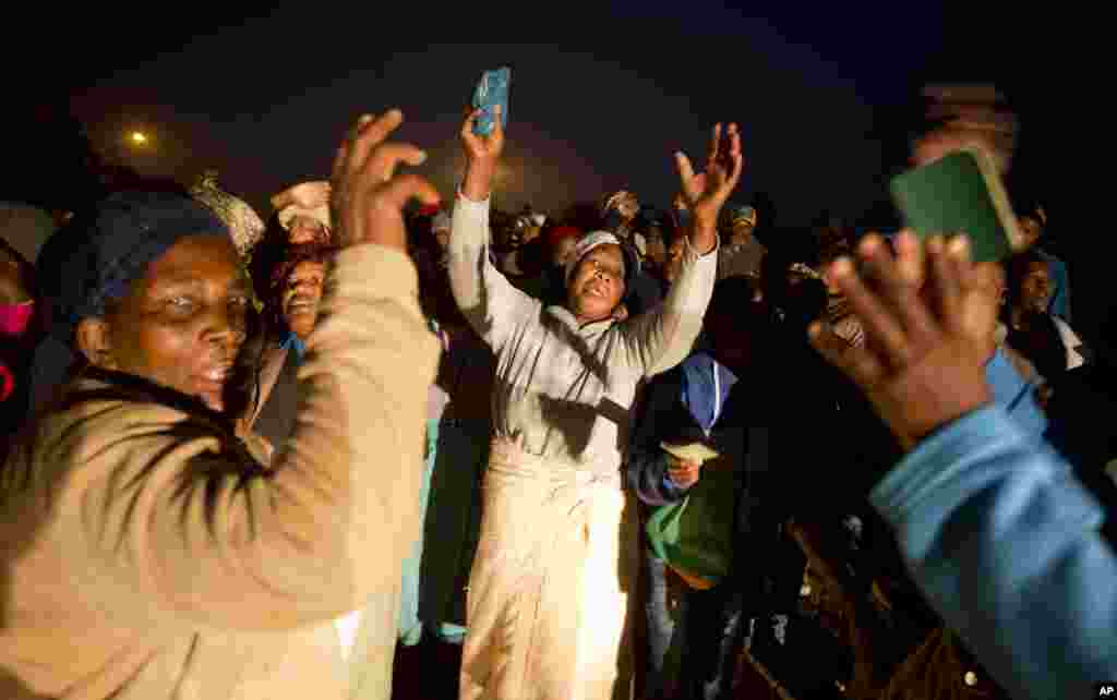 Voters dance and sing in the early hours while holding up their identification documents as they queue to vote at a polling station. The station was burned down overnight in the politically sensitive mining town of Bekkersdal, South Africa, May 7, 2014.