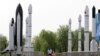 FILE - A woman walks with a child as they visit a park displaying replicas of foreign and domestic space vehicles in Beijing, China, June 26, 2016. 