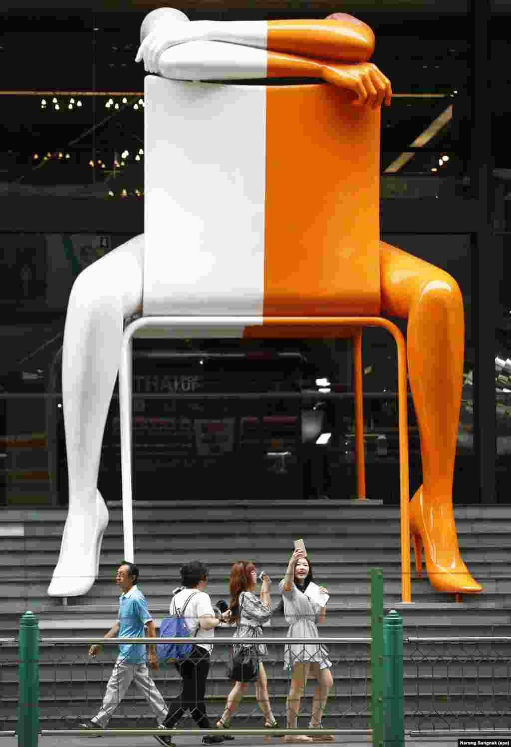 Tourists walk in front of an outdoor art installation at a shopping mall in Bangkok, Thailand.