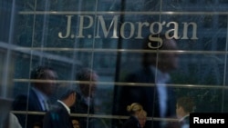 FILE - Workers are reflected in the windows of JP Morgan Chase offices.