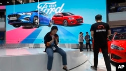 FILE - Visitors check out the Ford booth during the Auto China 2018 show, in Beijing, China, April 25, 2018.