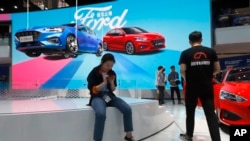 FILE - Visitors check out the Ford booth during the Auto China 2018 show, in Beijing, China, April 25, 2018.