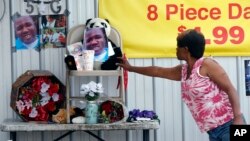A woman touches a makeshift memorial for Alton Sterling, outside a convenience store in Baton Rouge, Louisiana, July 6, 2016. Sterling was shot and killed by police outside the store.