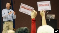 Audience members hold signs reading "DISAGREE" as U.S. Rep. Scott Perry, R-Pa., speaks during a town hall meeting, March 18, 2017, in Red Lion, Pa. Perry's event turned contentious in his conservative south-central Pennsylvania district over questions about his support for President Donald Trump's budget proposal and immigration plans and for undoing former President Barack Obama's signature health care law.