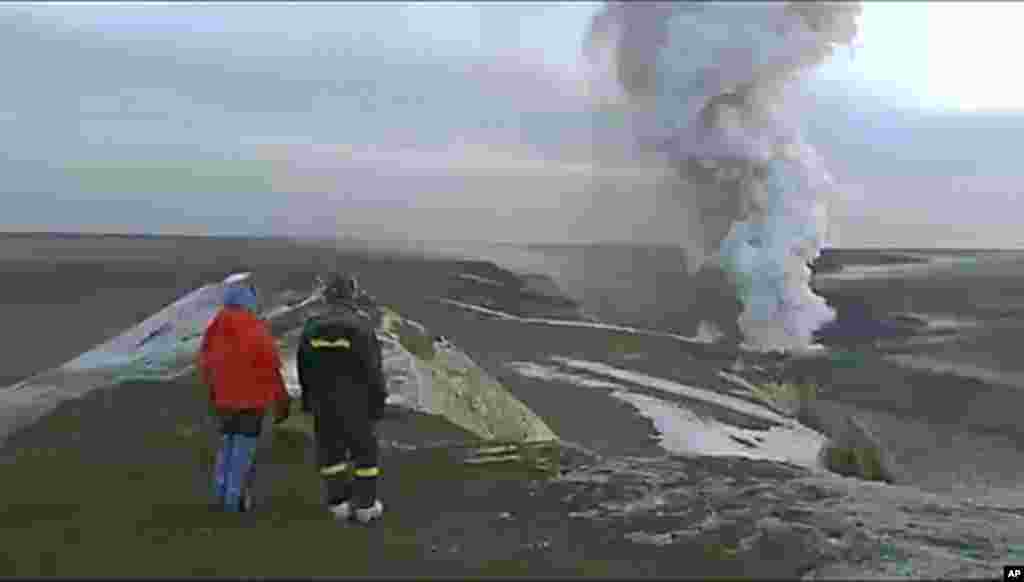 In this image from television, people watch a plume rising from the Grimsvotn volcano in Iceland, May 25 2011