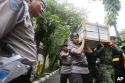FILE - Indonesian police officers and soldiers carry one of the coffins prepared for the victims of a military helicopter which crashed in Poso, Central Sulawesi, at hospital in Jakarta, Indonesia, March 21, 2016.