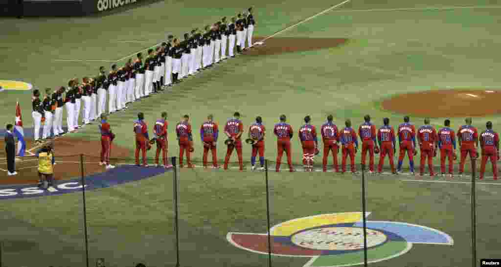 The Netherlands (top) and Cuban baseball teams offer a silent tribute to victims of March 11, 2011 earthquake and tsunam, before their World Baseball Classic (WBC) second round game in Tokyo, March 11, 2013. 