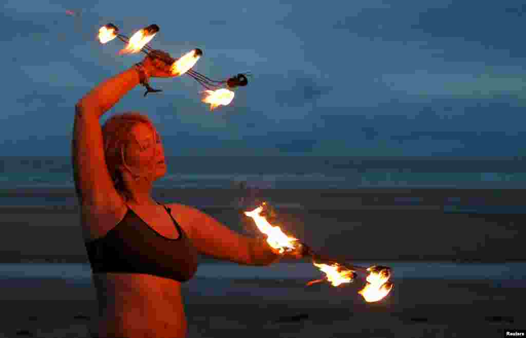 A participant in the annual North East Skinny Dip performs a fire display at Druridge Bay, Britain.