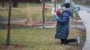 Femme priant devant le centre hospitalier de soins de longue durée Herron, où près de 50 personnes sont mortes du coronavirus, Dorval, Québec, Canada, 13 avril 2020. Une enquête publique a été ordonnée en juin. (REUTERS/ Christinne Muschi)
