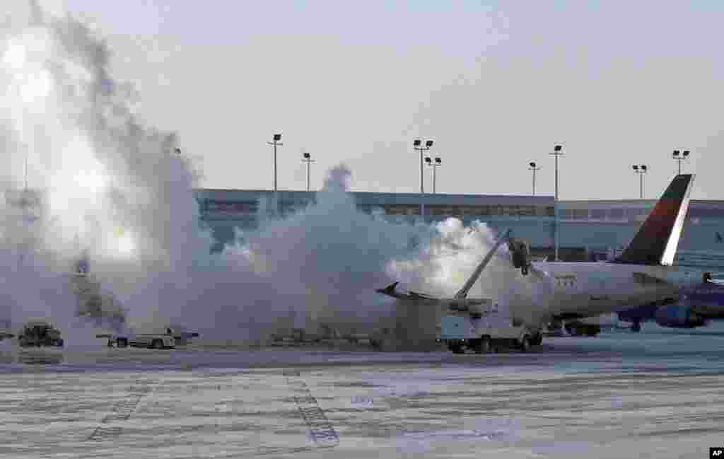 Sebuah mobil membersihkan es pada pesawat Delta di bandara internasional Midway, Chicago, Illinois, AS, setelah udara beku melanda kawasan tengah dan pantai Timur AS. 