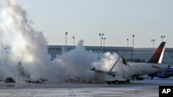 Sebuah pesawat maskapai Delta di bandara Chicago harus dibersihkan dari lapisan es (6/1). Beberapa maskapai membatalkan penerbangan di AS akibat suhu udara yang membeku.