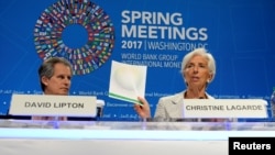 IMF Managing Director Christine Lagarde (R) holds up agenda papers as she attends a press briefing to open the IMF and World Bank's 2017 Annual Spring Meetings, with First Deputy David Lipton, in Washington, April 20, 2017. 