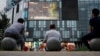 北京居民坐在一家商场外观看电视节目。（2016年7月16日）