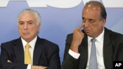 Brazil's President Michel Temer, left, sits next to the Governor of Rio de Janeiro Luiz Fernando Pezao, during the signing of a decree for the military intervention of Rio de Janeiro's local police, in Brasilia, Brazil, Feb. 16, 2018.