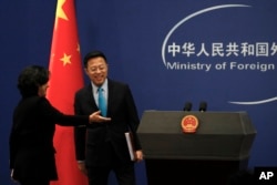 Chinese Foreign Ministry spokeswoman Hua Chunying, left, shows the way to their then new spokesman Zhao Lijian on stage during a daily briefing at the Ministry of Foreign Affairs office in Beijing on February 24, 2020. (Andy Wong/AP)