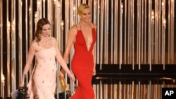 FILE - Emily Blunt, left, and Charlize Theron present an award at the Oscars in Los Angeles, Feb. 28, 2016. The actresses appear in "The Huntsman: Winter's War." 