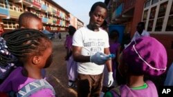 Wani Malami yana amfani da na’urar auna zafin jiki domin neman alamun cutar Ebola.