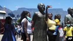 People take photos at a statue of Anglican Archbishop Desmond Tutu at the V&A Waterfront in Cape Town, South Africa, Dec. 26, 2021.
