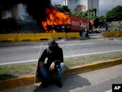 A demonstrator rests near a burning truck during a protest on the Francisco Fajardo highway outside La Carlota Air Base in Caracas, Venezuela, June 23, 2017.