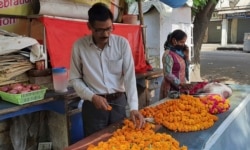 Mahesh Verma and his wife work at their flower stall outside a Hindu temple honoring the monkey god Hanuman in Lucknow, India, Friday, May 8, 2020. (AP Photo/Biswajeet Banerjee)