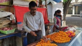 Mahesh Verma and his wife work at their flower stall outside a Hindu temple honoring the monkey god Hanuman in Lucknow, India, Friday, May 8, 2020. (AP Photo/Biswajeet Banerjee)