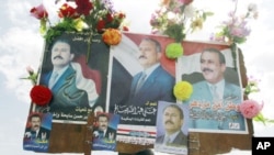 A supporter of Yemen's President Ali Abdullah Saleh holds up posters of Saleh after a rally to show support at the Tahrir Square in Sana'a, March 25, 2011