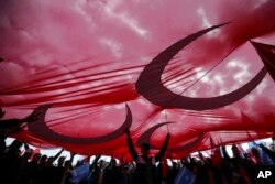Supporters hold a huge flag as they listen to Devlet Bahceli, the leader of Turkey's opposition Nationalist Movement Party, who supports President Recep Tayyip Erdogan, during a referendum rally in Istanbul, April 9, 2017.
