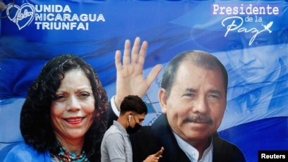 Un hombre revisa su teléfono mientras camina junto a una pancarta que promueve al presidente de Nicaragua, Daniel Ortega. [Foto de archivo]