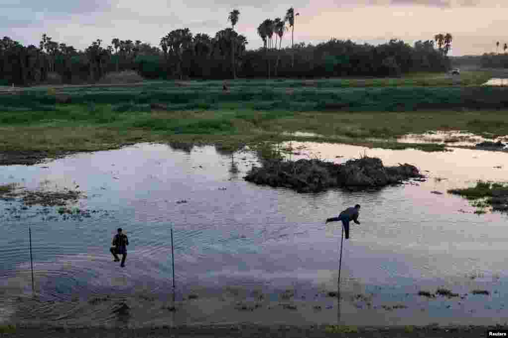 Migrants from Central America jump over a fence as they run south towards Mexico while being chased by a U.S. border patrol agent after crossing the Rio Grande river into the United States from Mexico in La Joya, Texas, May 23, 2021.