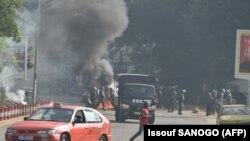 La police anti-émeute ivoirienne disperse les manifestants qui ont brûlé des barricades sur la route lors d'une manifestation contre le troisième mandat du président Alassane Ouattara dans le quartier de la Riviera Anono à Abidjan, le 13 août 2020. ( Issouf SANOGO / AFP)