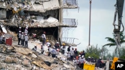 Rescue workers search in the rubble at the Champlain Towers South condominium, Monday, June 28, 2021, in the Surfside area of Miami. (AP Photo/Lynne Sladky)