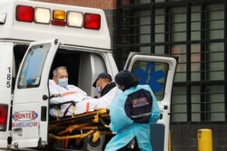 Técnicos de emergencias médicas suben a un paciente en una ambulancia fuera del Centro Hospitalario Elmhurst,en Nueva York, en medio de un brote de la COVID-19.