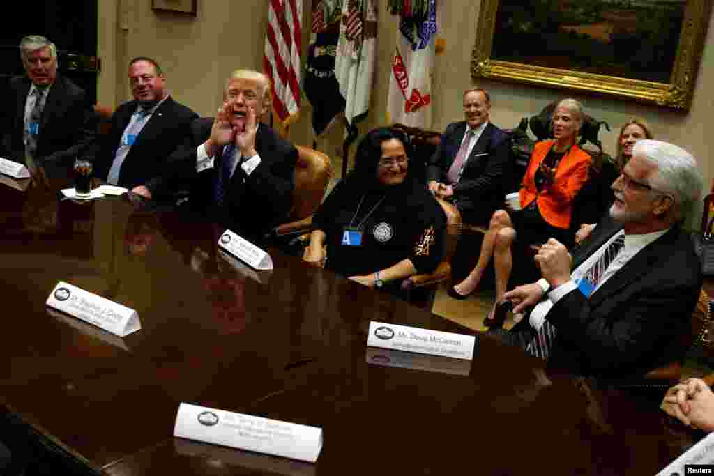 U.S. President Donald Trump calls departing reporters back into the room as United Brotherhood of Carpenters General President Doug McCarron (R) begins to compliment him on his inaugural address, during a roundtable meeting with labor leaders at the White House in Washington, D.C., Jan. 23, 2017.