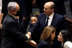 Benjamin Netanyahu (L) greets new Israel Prime minister Naftali Bennett following the vote on the new coalition at the Knesset, Israel's parliament, in Jerusalem June 13, 2021. (REUTERS/Ronen Zvulun)